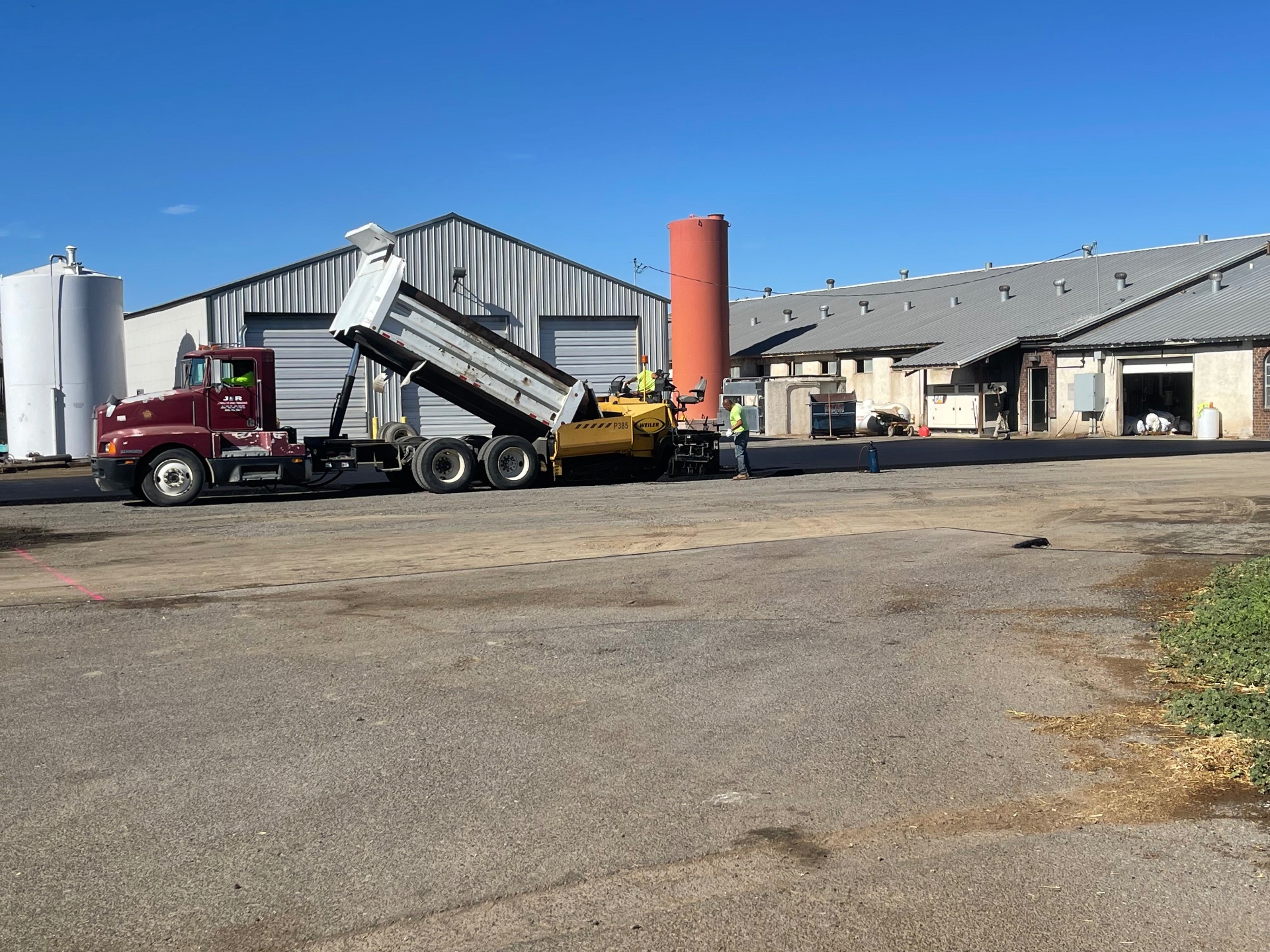 Dump truck unloading asphalt at a dairy facility